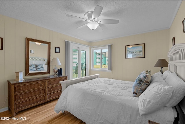 bedroom featuring ornamental molding, a textured ceiling, light wood-type flooring, and ceiling fan