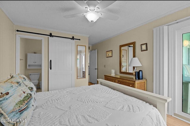 bedroom with connected bathroom, a barn door, ornamental molding, and ceiling fan