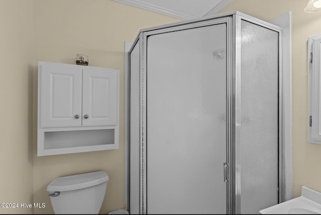 bathroom with a shower with door, toilet, and ornamental molding