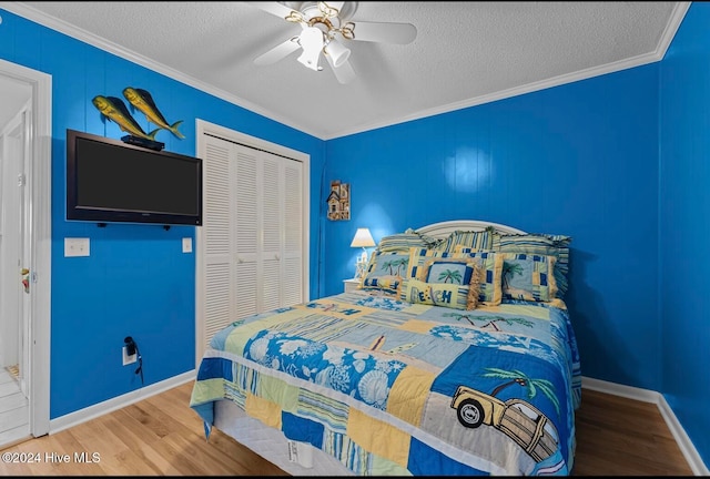 bedroom with a textured ceiling, a closet, ceiling fan, hardwood / wood-style flooring, and ornamental molding