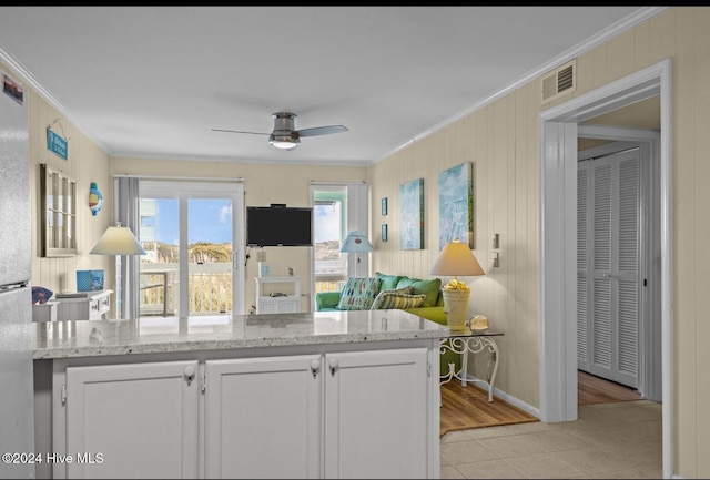 kitchen with light hardwood / wood-style flooring, crown molding, white cabinets, and ceiling fan