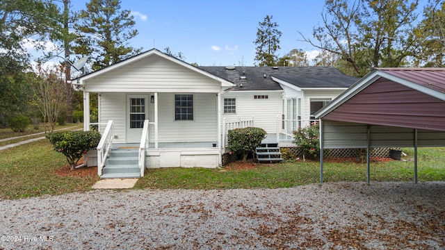 rear view of property featuring a porch, a lawn, and a carport