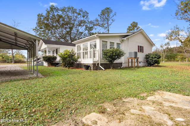 back of house featuring a sunroom, central AC, a yard, and a carport