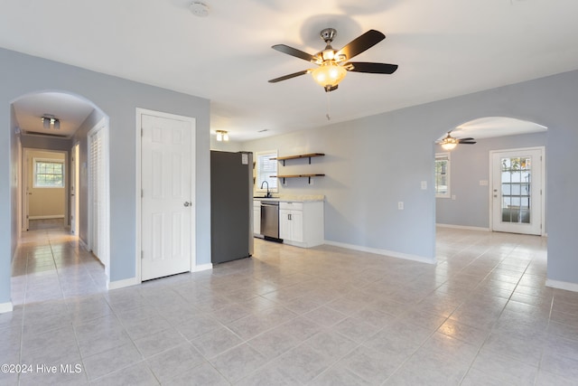 unfurnished living room with a wealth of natural light, ceiling fan, sink, and light tile patterned flooring