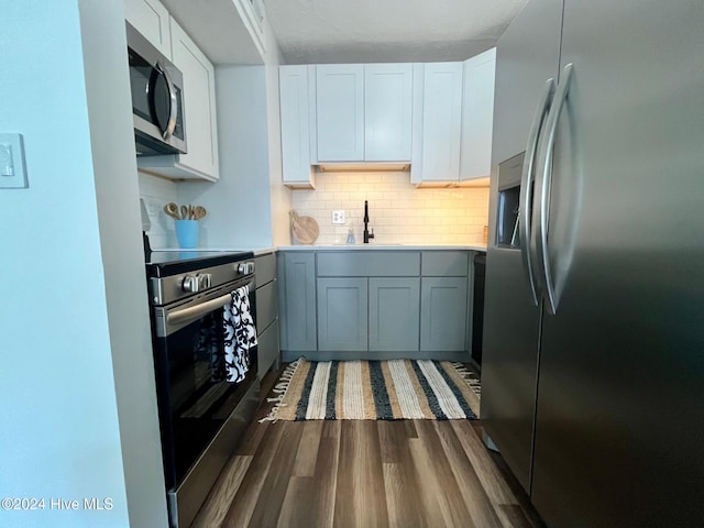 kitchen with tasteful backsplash, stainless steel appliances, dark wood-type flooring, white cabinets, and sink