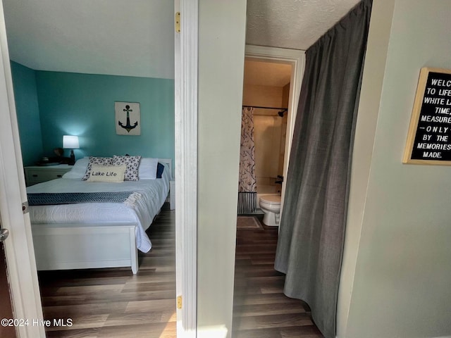 bedroom featuring ensuite bath, a textured ceiling, and dark hardwood / wood-style floors