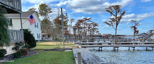 view of dock with a yard and a water view