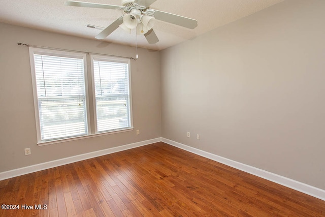 empty room with ceiling fan, hardwood / wood-style flooring, and a textured ceiling