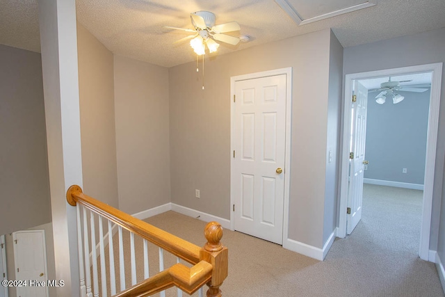 hall featuring a textured ceiling and light colored carpet