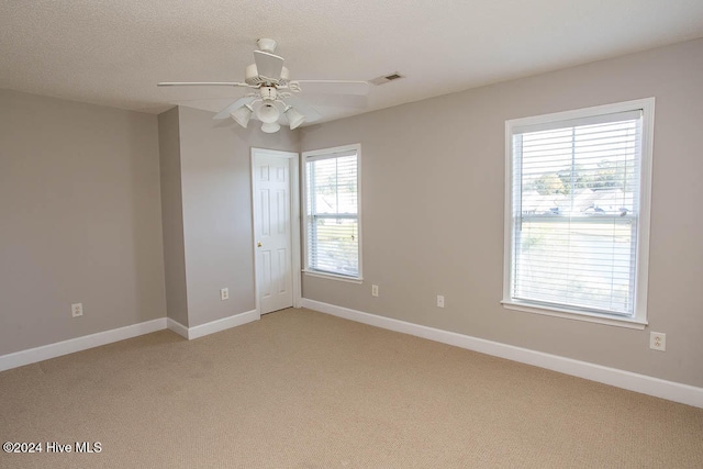 carpeted spare room with ceiling fan, a textured ceiling, and plenty of natural light