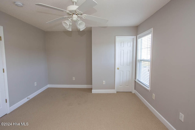 carpeted empty room with ceiling fan and a textured ceiling