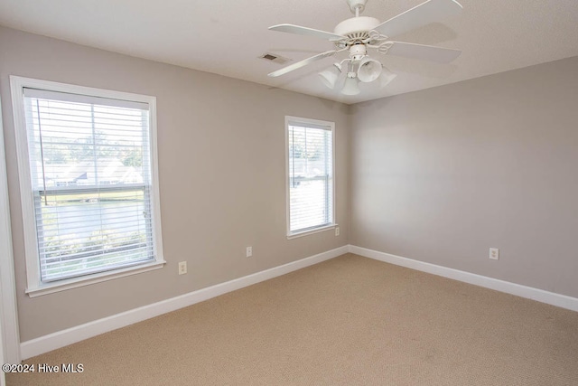 carpeted spare room with a wealth of natural light and ceiling fan