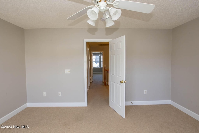 carpeted spare room featuring a textured ceiling and ceiling fan