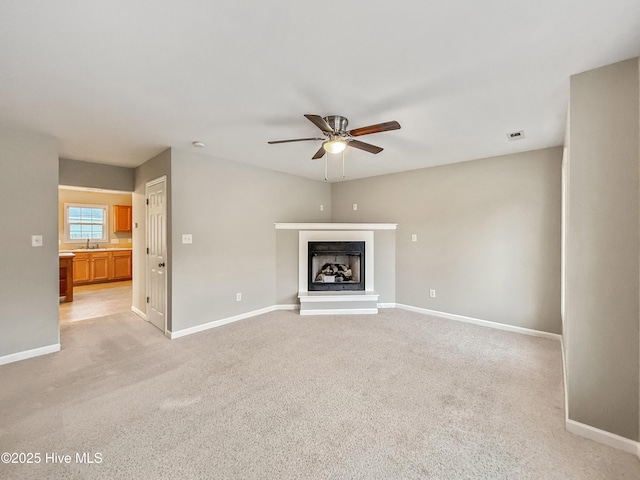 unfurnished living room with ceiling fan, sink, and light carpet