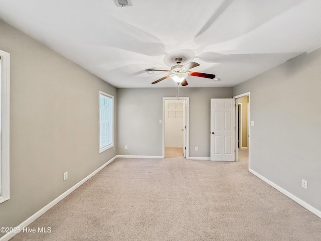 unfurnished bedroom featuring ceiling fan, light colored carpet, and a walk in closet