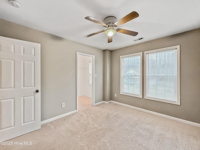 unfurnished bedroom with light carpet, a spacious closet, a closet, and ceiling fan