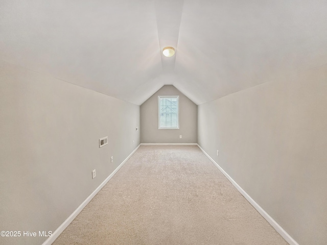 additional living space featuring lofted ceiling and light colored carpet