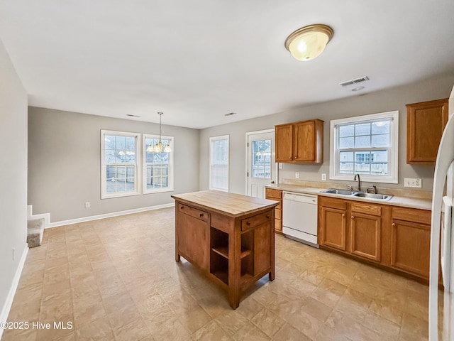 kitchen featuring hanging light fixtures, a kitchen island, sink, and white dishwasher