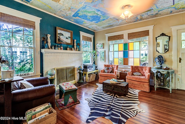 sitting room with ornamental molding, dark hardwood / wood-style floors, a healthy amount of sunlight, and a brick fireplace