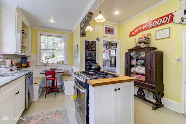 kitchen with appliances with stainless steel finishes, a center island, white cabinetry, wooden counters, and ornamental molding