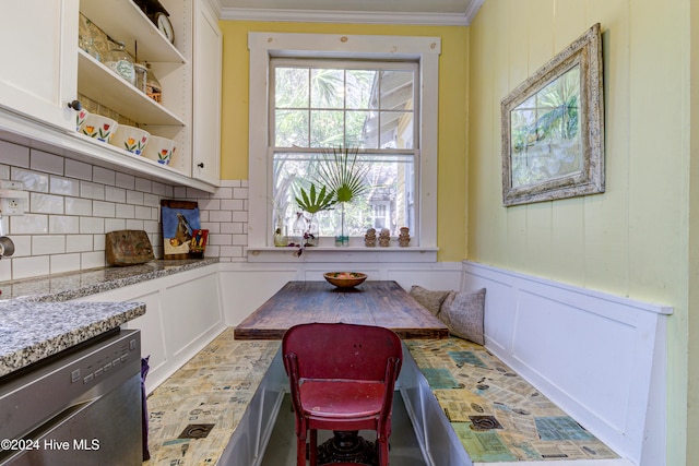 kitchen featuring white cabinetry, decorative backsplash, stainless steel dishwasher, and breakfast area