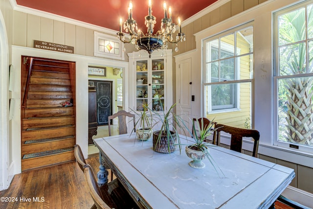 dining area featuring a wealth of natural light, ornamental molding, wood-type flooring, and an inviting chandelier