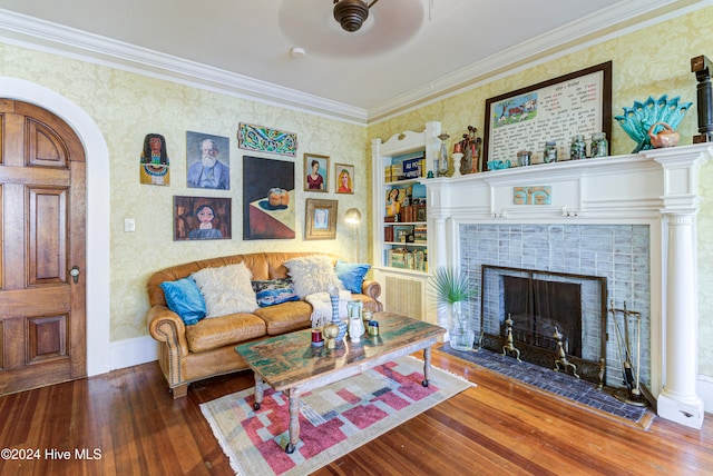 living room featuring crown molding, dark wood-type flooring, a fireplace, and built in shelves