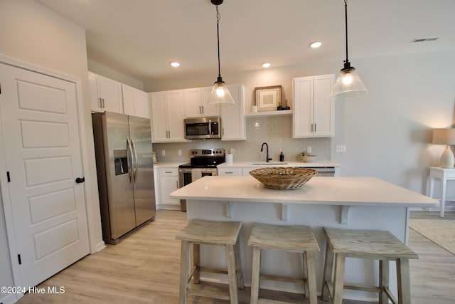 kitchen with stainless steel appliances, a kitchen bar, tasteful backsplash, light countertops, and recessed lighting