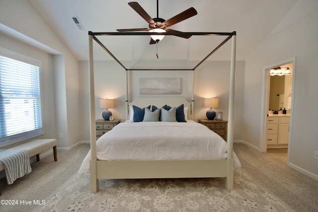 bedroom featuring light colored carpet, lofted ceiling, baseboards, ensuite bath, and ceiling fan