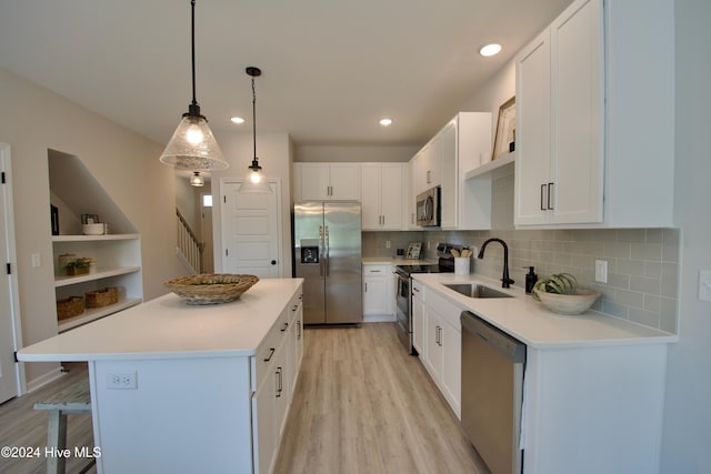 kitchen featuring appliances with stainless steel finishes, a sink, light wood-type flooring, a kitchen island, and white cabinets