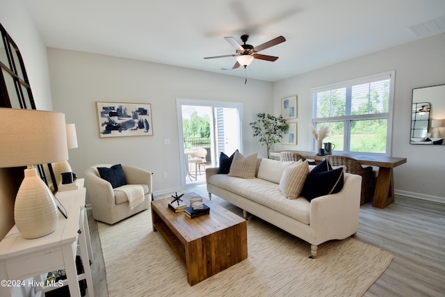 living area featuring baseboards, light wood-style flooring, and ceiling fan