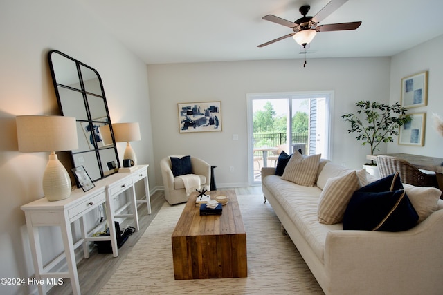 living area featuring a ceiling fan, light wood finished floors, and baseboards
