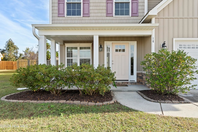 property entrance with a garage, a yard, and covered porch