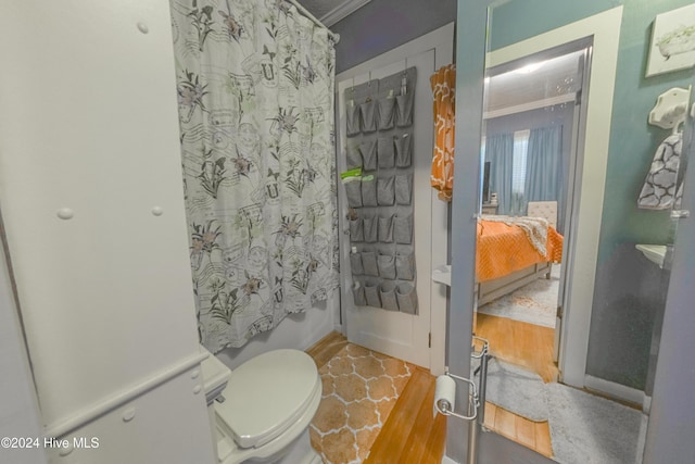 bathroom with toilet, hardwood / wood-style flooring, ornamental molding, and shower / bath combo