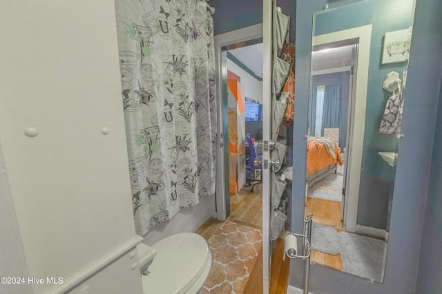 bathroom featuring toilet, shower / tub combo with curtain, and wood-type flooring