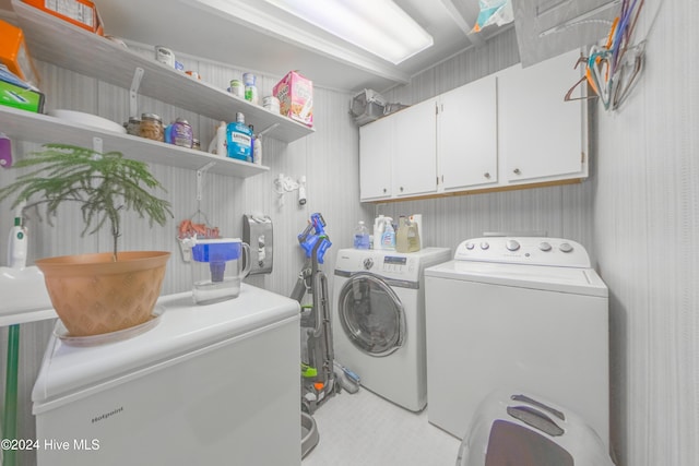 laundry area featuring washer and dryer, light tile patterned flooring, and cabinets