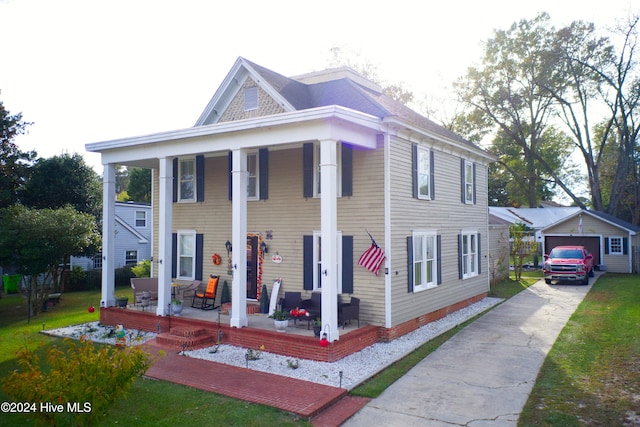 view of front of house featuring a front yard, a garage, a porch, and an outdoor structure