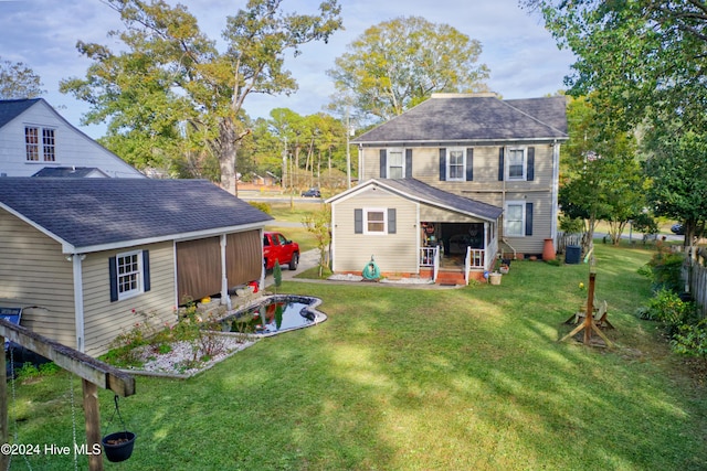 rear view of house with central air condition unit and a lawn