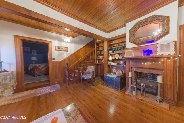 living room featuring wood walls, wood ceiling, hardwood / wood-style floors, a fireplace, and built in features