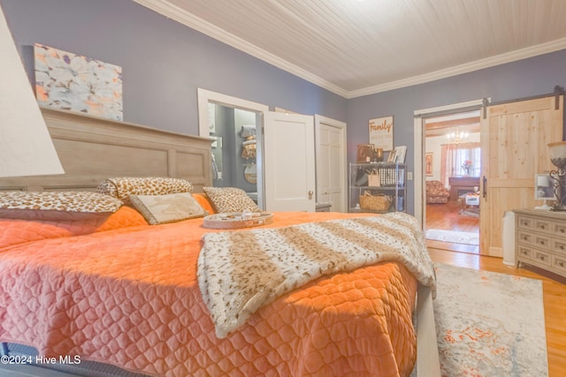 bedroom with light hardwood / wood-style floors, ornamental molding, and a barn door