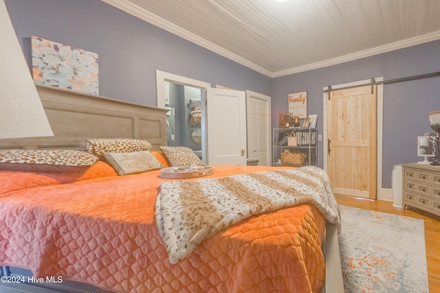 bedroom featuring crown molding, light hardwood / wood-style floors, and a barn door