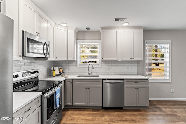 kitchen featuring hanging light fixtures, sink, stainless steel appliances, and white cabinetry