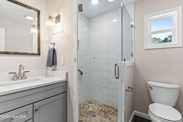 bathroom with toilet, a shower with shower door, and vanity