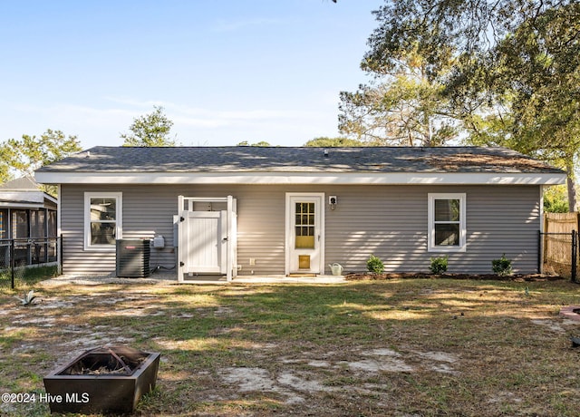 back of property featuring an outdoor fire pit and a yard