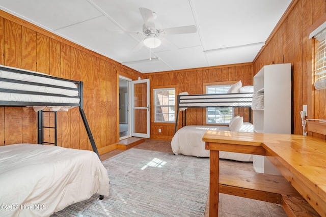 bedroom with wood walls, ceiling fan, and light colored carpet