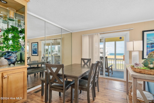 dining space with ornamental molding, light hardwood / wood-style flooring, a water view, and plenty of natural light