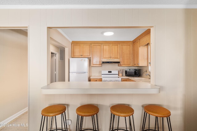 kitchen featuring kitchen peninsula, sink, white appliances, and a breakfast bar