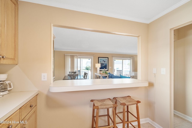 kitchen featuring light brown cabinets, a kitchen breakfast bar, and ornamental molding