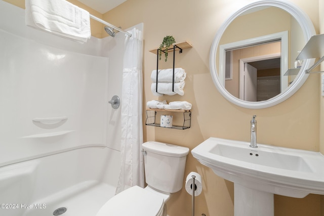 bathroom featuring toilet, sink, and a shower with shower curtain