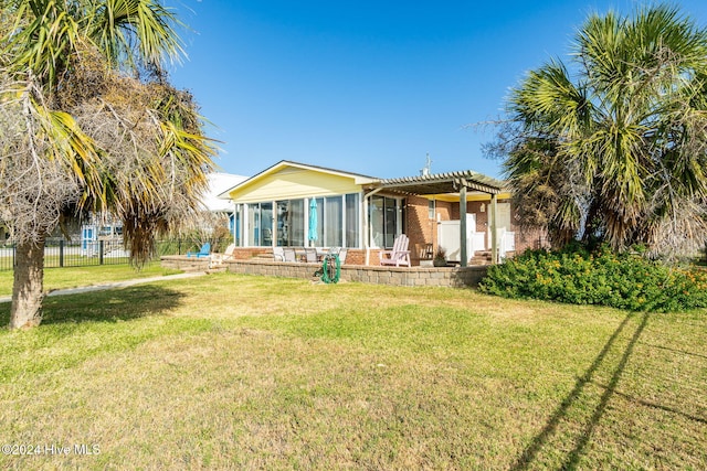 rear view of house with a lawn, a sunroom, and a pergola